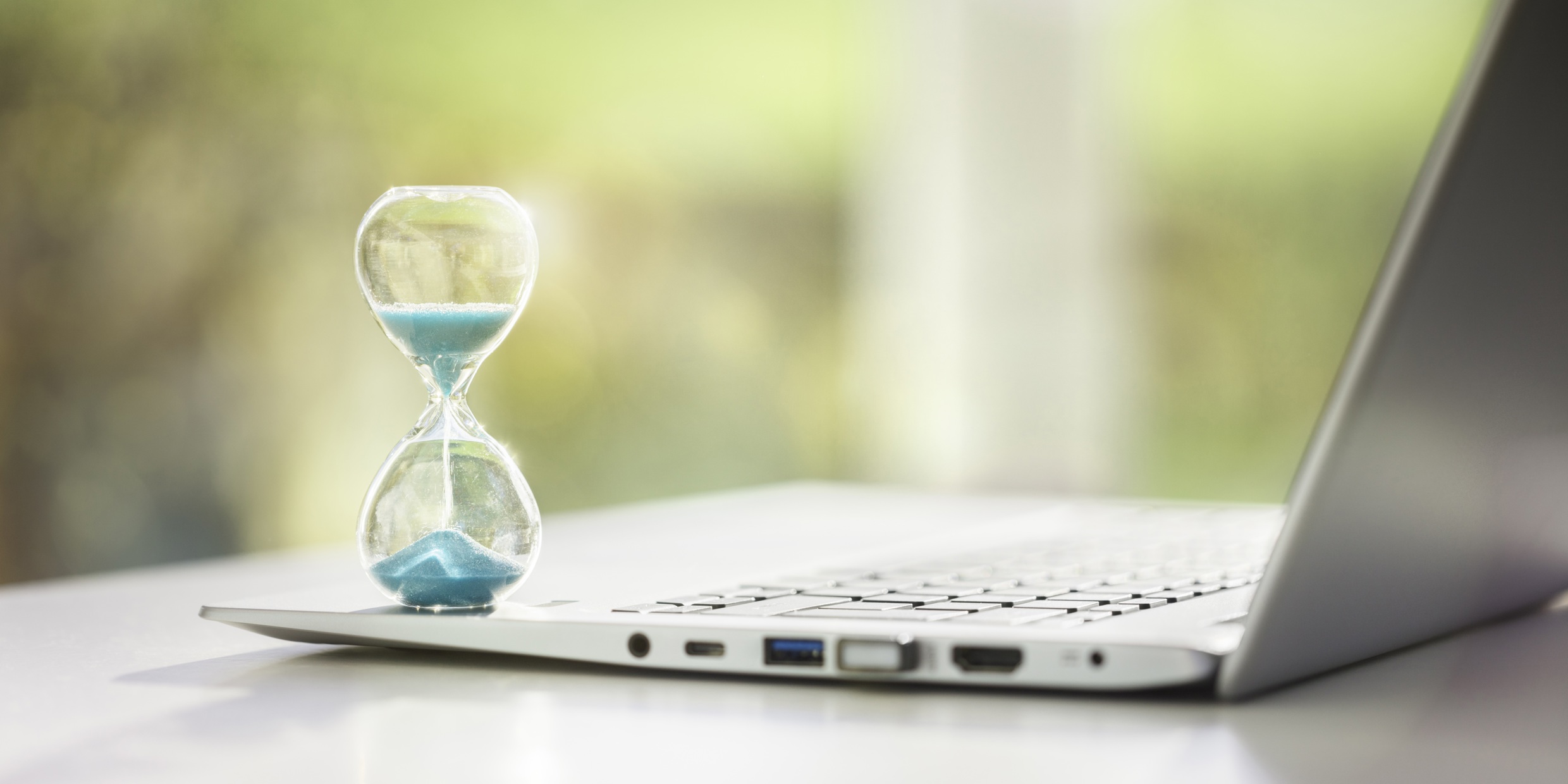 Laptop mit Sanduhr als Symbol der Arbeitszeit